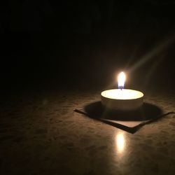 Lit candle in dark room