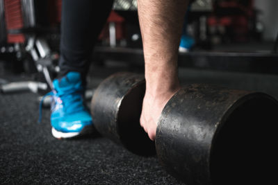 Close-up of man hand picking dumbbell in gym