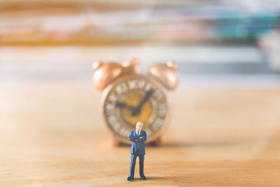 Close-up of figurine against clock on table