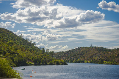 Scenic view of lake by mountains against sky