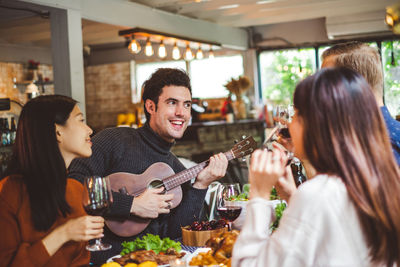 Man playing guitar with friends at restaurant