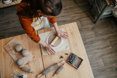 Woman potter in her workshop, rolling out clay