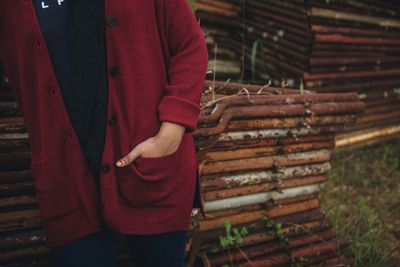 Midsection of woman standing against rusty metals on field