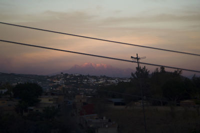 Silhouette buildings in town against sky at sunset