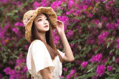 Beautiful woman standing by pink flowering plants