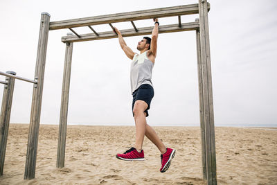 Young man exercising on monkey bars on the beach