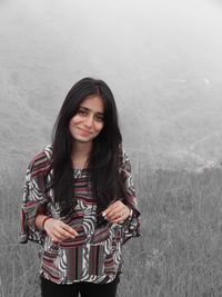 Portrait of smiling young woman standing against the hill