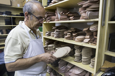 Shoemaker selecting shoe soles from a shelf in his workshop