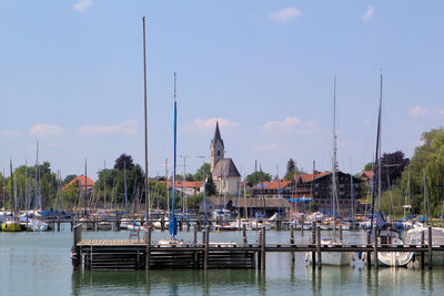 Sailboats moored at harbor against sky