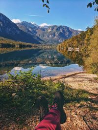 Low section of person by lake against mountains