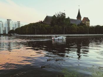 Scenic view of lake by buildings against sky in city