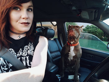Portrait of young woman with dog sitting in car