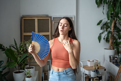 Portrait of smiling young woman standing against wall