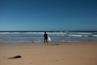 Man with surfboard at beach on sunny day