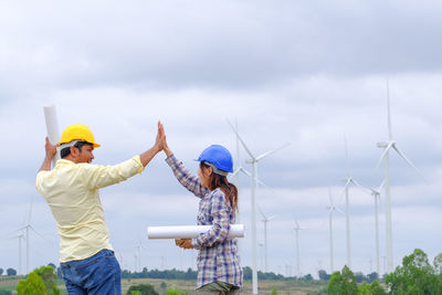 Man holding woman standing against sky