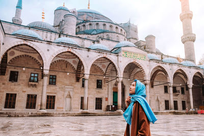 Rear view of woman walking against historic building