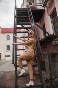 Full length outside portrait of fashion model in sunglasses, beige summer spring suit in urban area