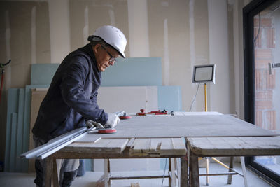 Construction worker with sheetrock on workbench at site