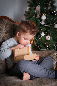Little boy opens a christmas present. christmas celebration, christmas tree.