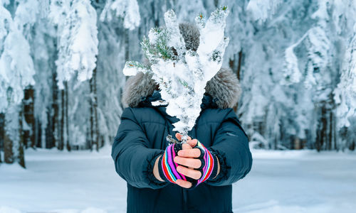 Person holding frozen twig in winter forest