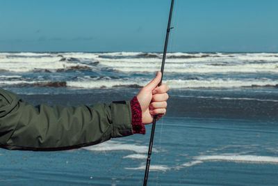 Close-up of hand holding fishing net against sea