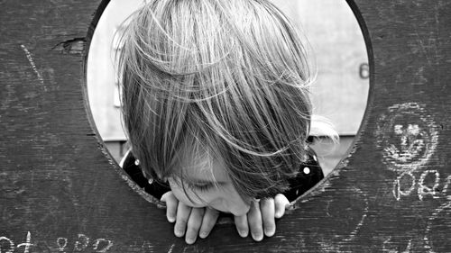 Close-up of boy looking through wooden hole