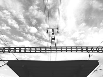 Low angle view of station roof and power lines against sky