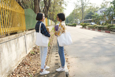 Side view of girls talking while standing on road