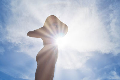 Low angle view of woman in bikini standing against sky