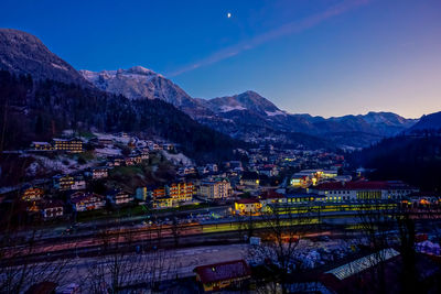 Illuminated buildings in city against clear sky at dusk