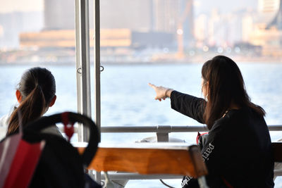 Rear view of women sitting in glass window