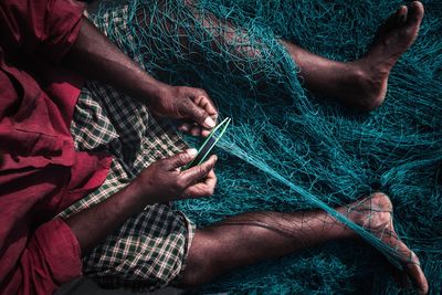 High angle view of man repairing fishing net