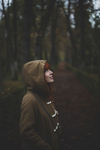 Portrait of young woman standing against trees