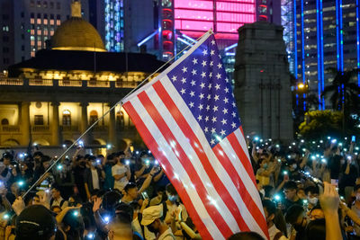 Crowd on illuminated street amidst buildings in city at night