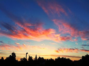 Low angle view of silhouette trees against dramatic sky