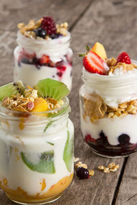 Yogurts with kiwis and berries in jars on table