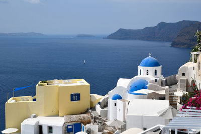 Buildings by sea against sky