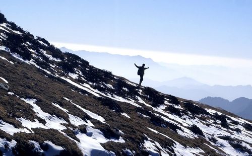 Silhouette man on snowcapped mountain against sky