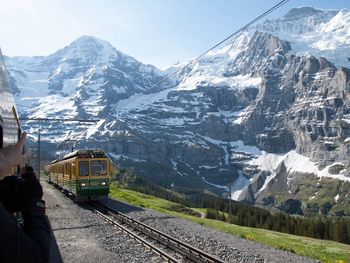 Train on railroad track by snowcapped mountains against sky