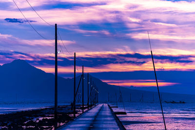 Pier over sea against sky during sunset