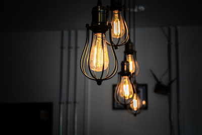 Close-up of illuminated light bulb hanging on wall