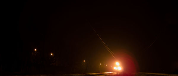 Illuminated road against sky at night