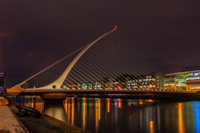 Illuminated bridge over river against sky at night