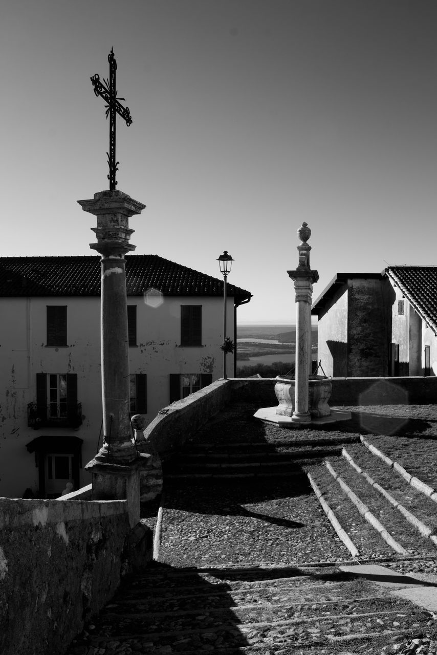 CROSS AMIDST BUILDINGS AGAINST SKY