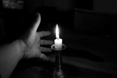 Cropped hand gesturing by illuminated candle