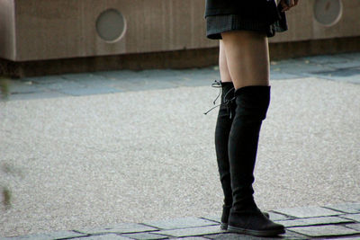 Low section of woman standing on footpath