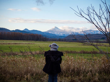 Rear view of woman standing on field against sky