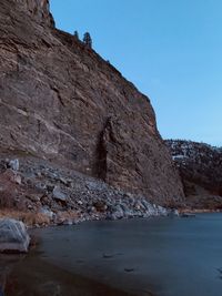 Rock formations on shore against clear sky