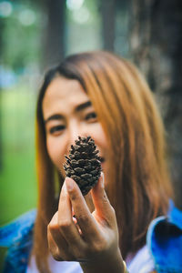 Close-up portrait of woman holding pine cone
