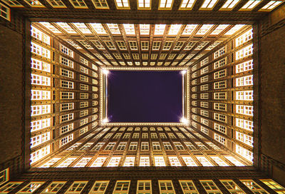 Directly below shot of illuminated modern building against sky at night